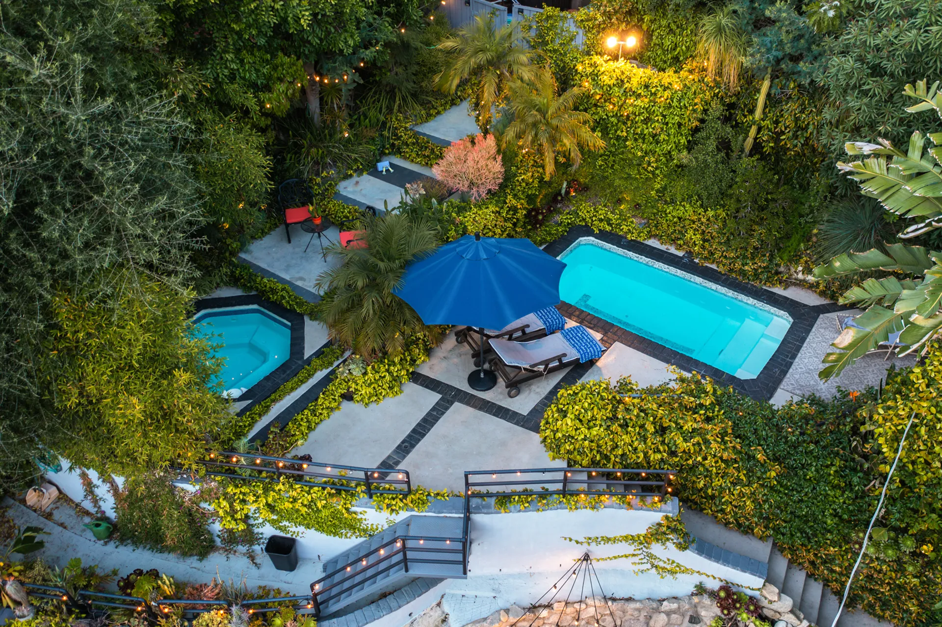 Backyard with two swimming pools, patio furniture, and surrounding plants