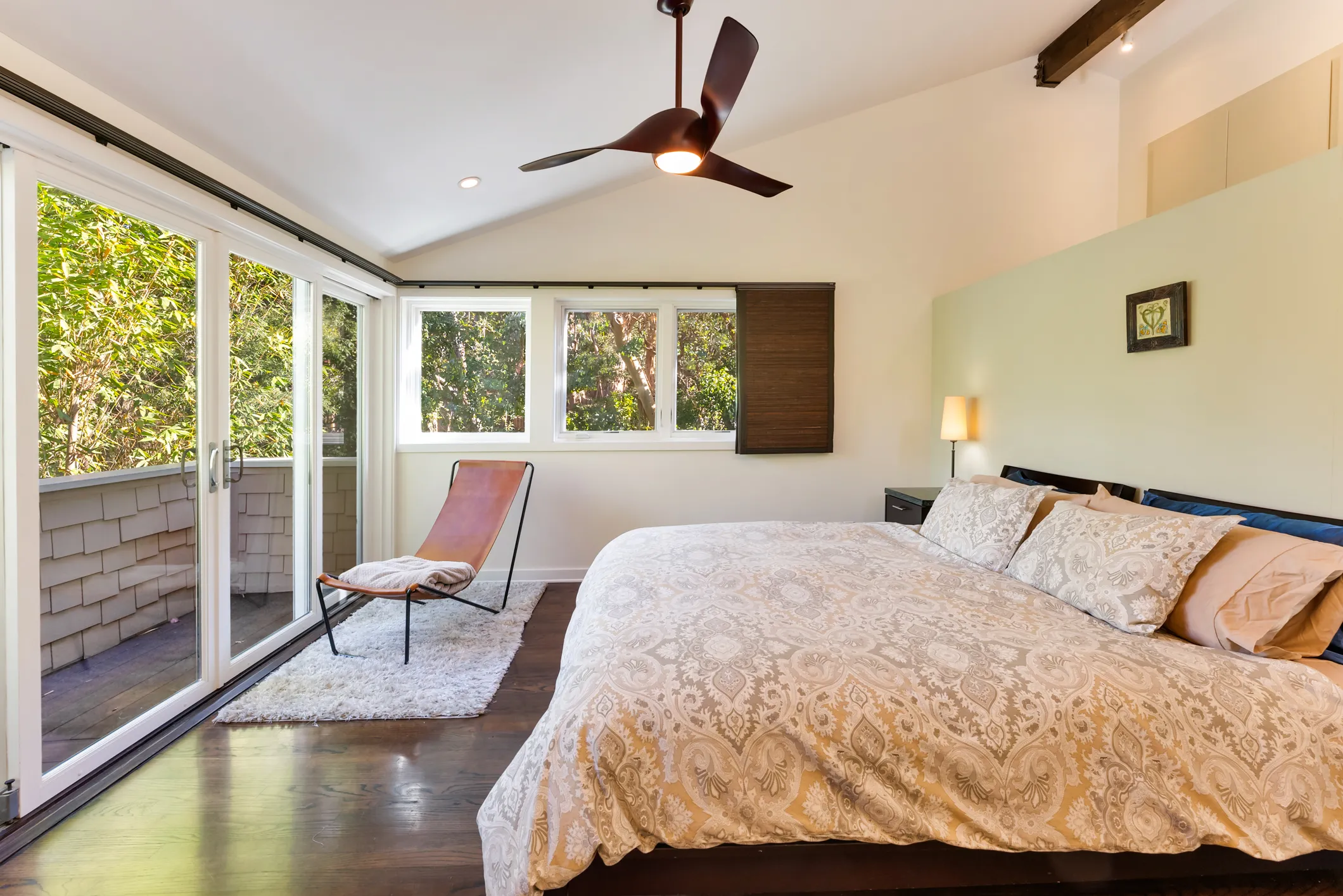 Bedroom with large bed, ceiling fan, chair, and sliding doors to the outside